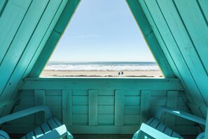 Une vue sur la plage depuis une chambre aux murs turquoise et aux bancs en bois.