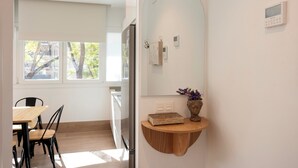 Eine moderne Küche mit Einbauofen, ein Essbereich mit Holztisch und -stühlen sowie ein großes Fenster mit Blick auf Bäume.