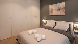 Ein Schlafzimmer mit Bett, Nachttischlampen, einem Gemälde und einem Kleiderschrank.