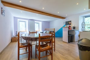 A dining area with a wooden table and chairs, a kitchen with a microwave, and a trash bin.