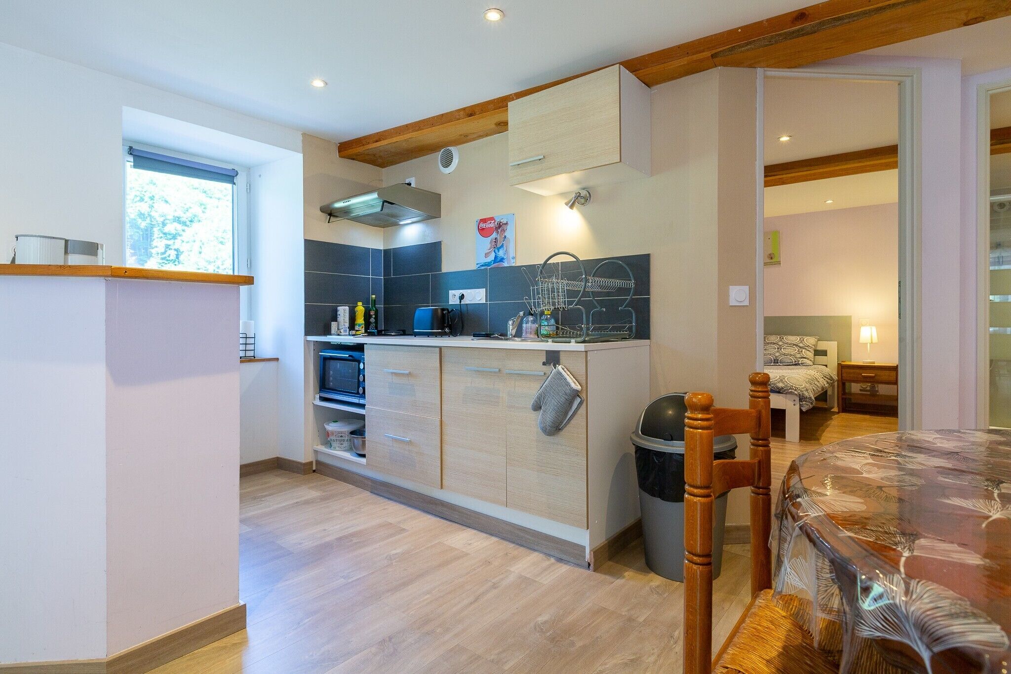 Une cuisine compacte avec des meubles en bois, un four encastré et un coin repas comprenant une table et des chaises.