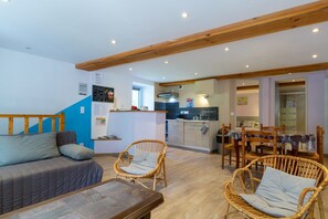 A cozy living area with a sofa, wicker chairs, a dining table, and a kitchen in the background. - Apartment in a Vercors Hamlet with Shared Terrace and Wi-Fi (Saint-Agnan-en-Vercors)