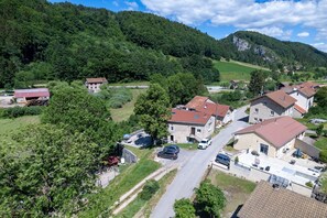 A residential area with houses, a road, and a forested hill in the background. - Apartment 'Dans Hameau Du Vercors' with Shared Terrace and Wi-Fi (Saint-Agnan-en-Vercors)