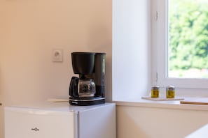 A coffee maker on a white appliance, a window with a view, and two condiment containers on a windowsill. - Apartment 'Dans Hameau Du Vercors' with Shared Terrace and Wi-Fi (Saint-Agnan-en-Vercors)