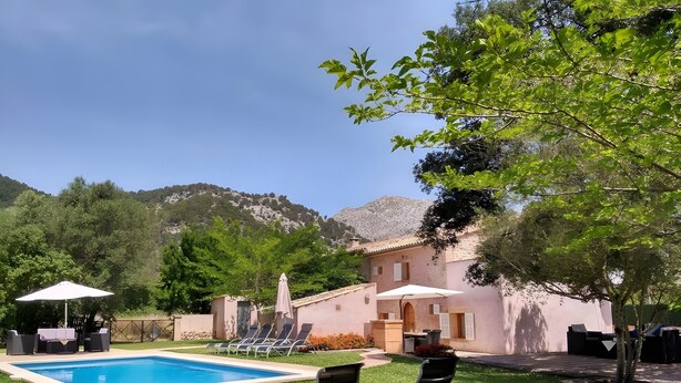 A swimming pool with lounge chairs, a patio area, and a building with a mountain backdrop. - Villa 'Can Bandris' with Mountain View, Wi-Fi and Air Conditioning (Illes Balears)