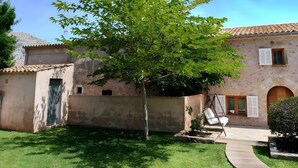 A rustic building with a tiled roof, a small tree in the courtyard, and a paved pathway. - Villa 'Can Bandris' with Mountain View, Wi-Fi and Air Conditioning (Illes Balears)