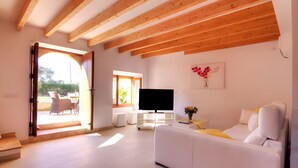 A modern living room with a white sofa, a flat-screen TV, and a wooden ceiling. - Villa 'Can Bandris' with Mountain View, Wi-Fi and Air Conditioning (Illes Balears)