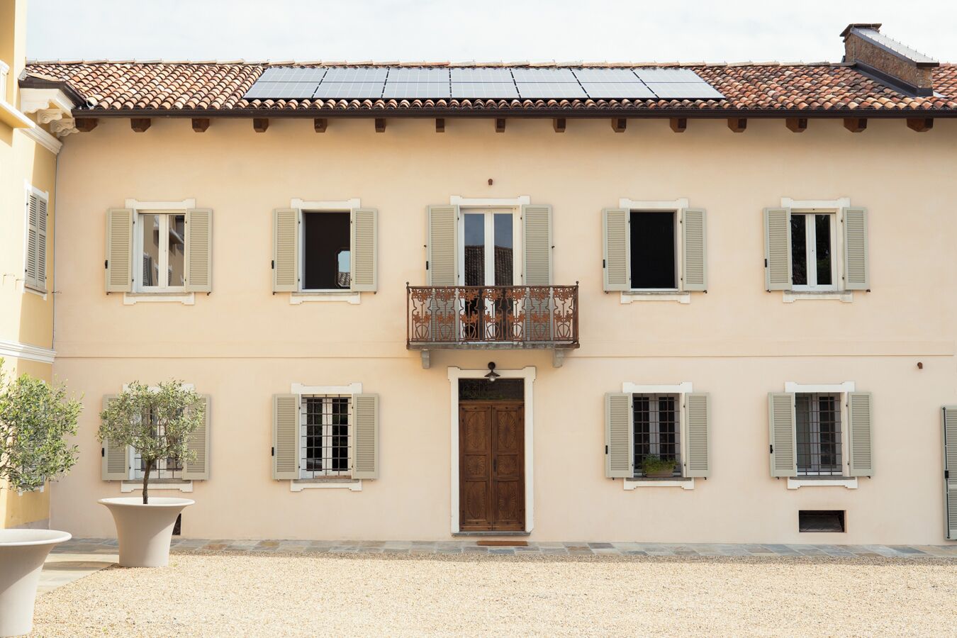 Un bâtiment à deux étages doté d’une entrée centrale, de nombreuses fenêtres avec volets, d’un balcon orné de balustrades et d’un toit recouvert de tuiles.