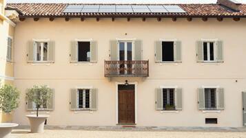 Un bâtiment à deux étages doté d’une entrée centrale, de nombreuses fenêtres avec volets, d’un balcon orné de balustrades et d’un toit recouvert de tuiles.