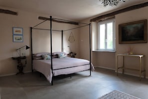 Un lit à baldaquin avec une literie à rayures, une table de chevet avec une lampe, une petite statue et un tableau accroché au mur.