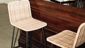 Un área de bar con sillas de mimbre, una botella de vino y un juego de té.