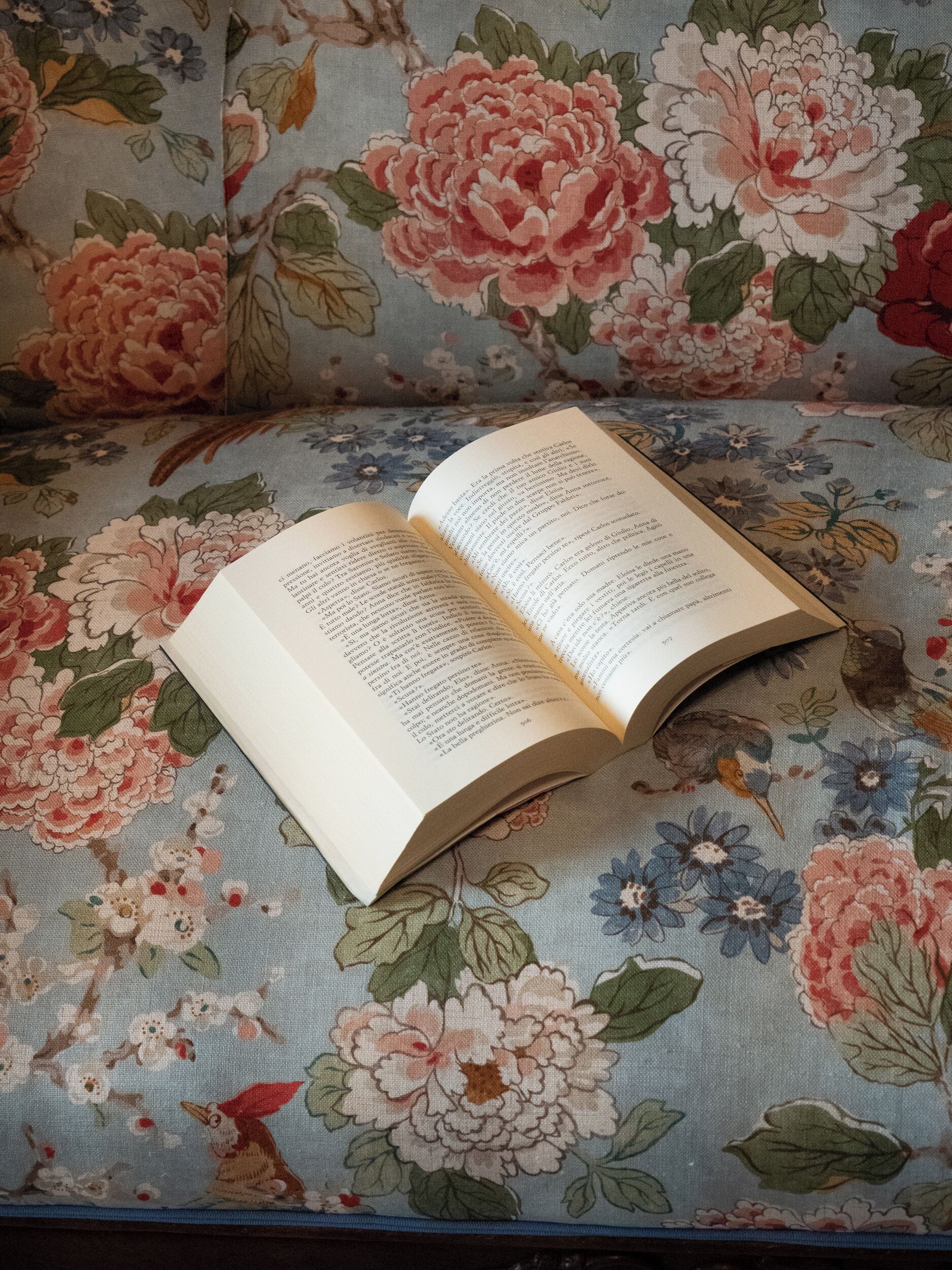 An open book on a floral-patterned fabric surface.