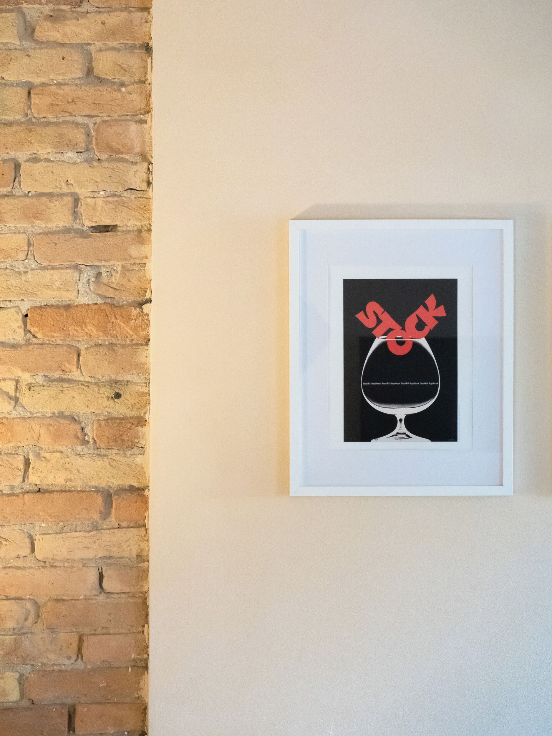 A framed artwork of a wine glass with a red design on a wall.