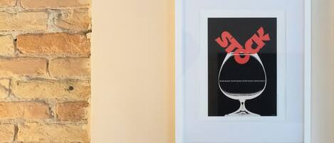 A framed artwork of a wine glass with a red design on a wall.