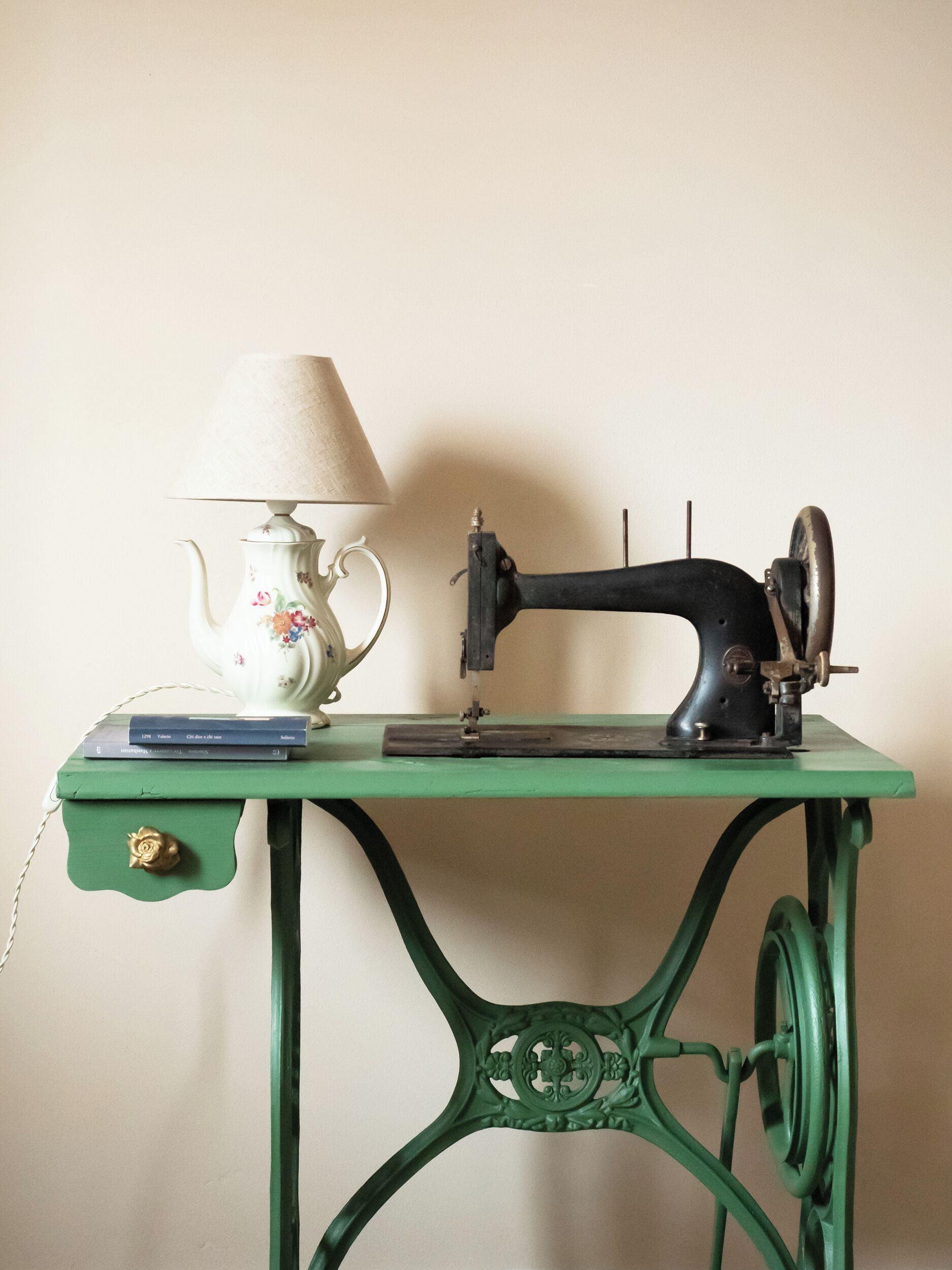 Een groene metalen tafel met een naaimachine en een lamp erop.