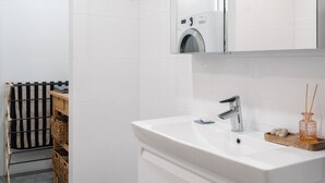 Ein modernes Badezimmer mit einem weißen Waschtisch, einem großen Spiegel und einer Duschkabine.