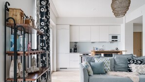 Ein modernes Wohnzimmer mit einem grauen Sofa, gemusterten Kissen und einem Holzregal mit verschiedenen Gegenständen.