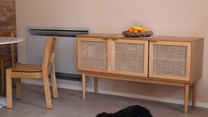 Een kamer met een houten kast, een stoel, een klein tafeltje en een zwarte hond.