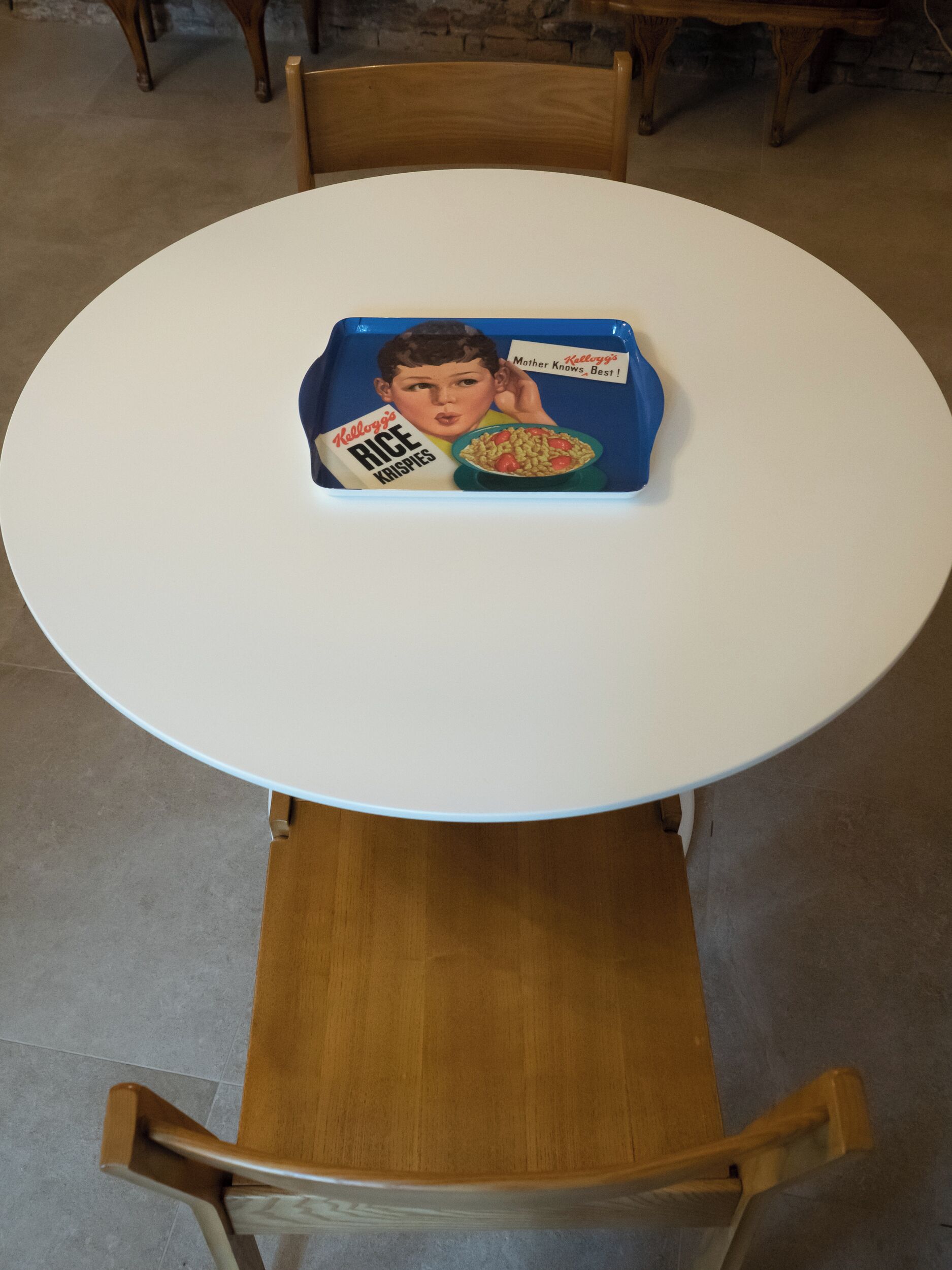 Ein runder, weißer Tisch mit einer blauen Ablage und einer Retro-Cereal-Box.