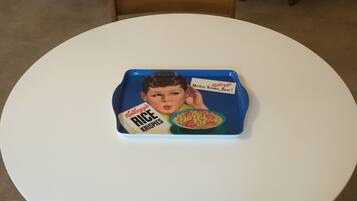 Ein runder, weißer Tisch mit einer blauen Ablage und einer Retro-Cereal-Box.