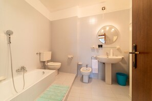 A modern bathroom with a bathtub, toilet, bidet, and sink. - Gaia Apartment Lakeview & garden (Bellagio)