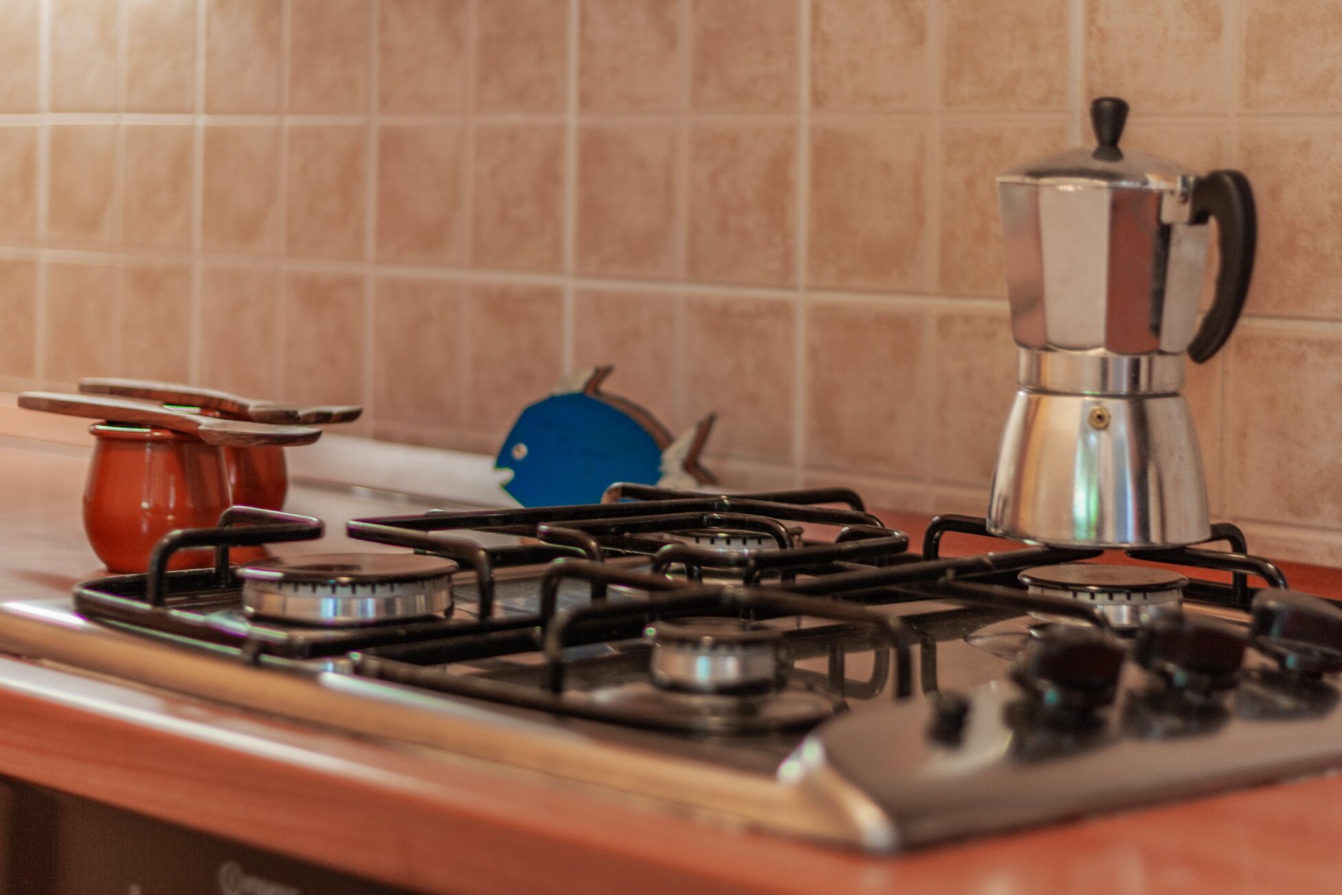 A kitchen with a gas stove, a coffee maker, and a pot.