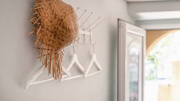 A wall-mounted rack with a woven basket and white hangers.