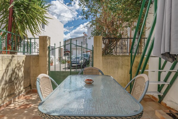 Une terrasse avec une table et des chaises, une vue sur la rue et un bâtiment en arrière-plan.
