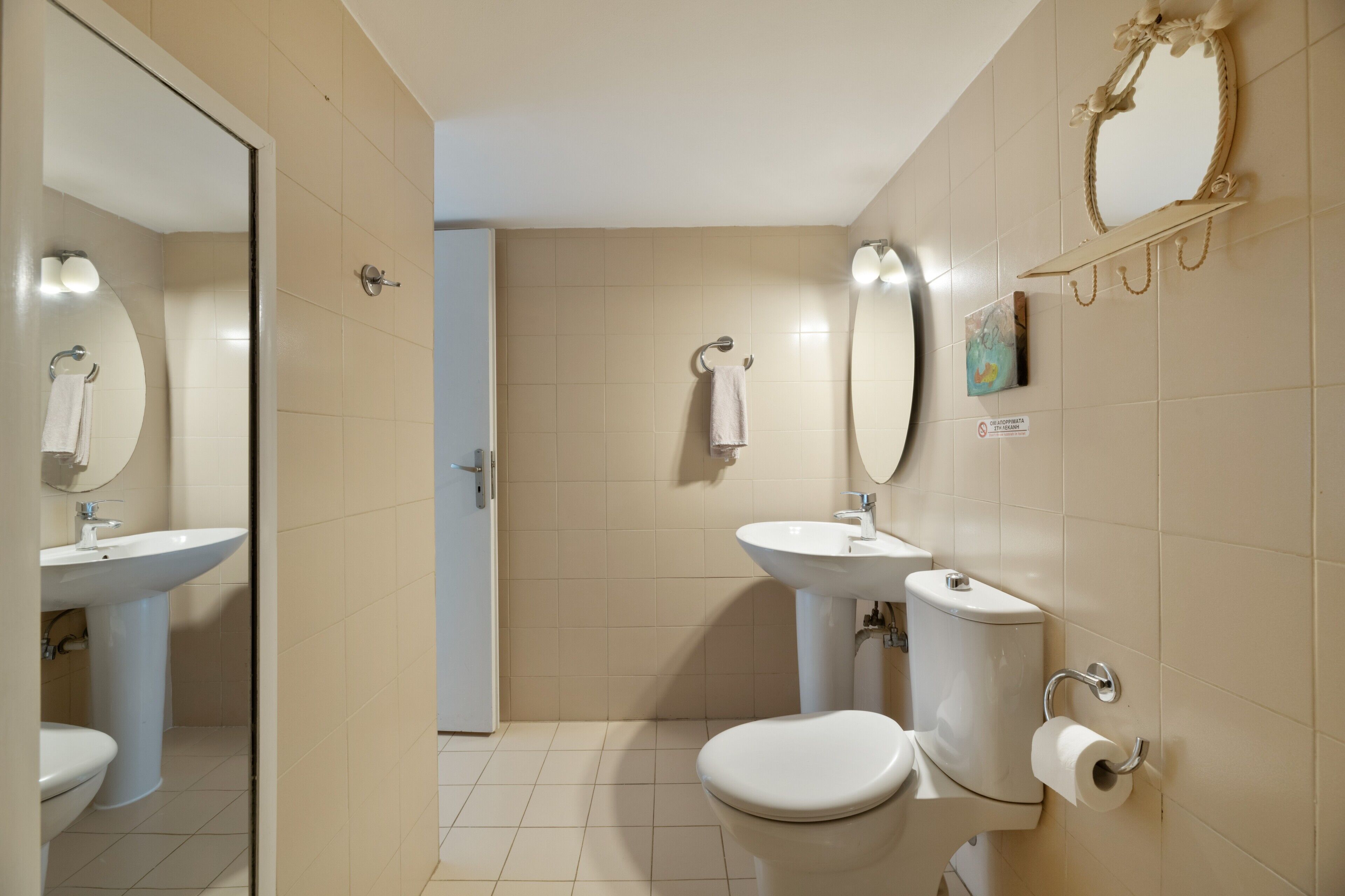A bathroom with a toilet, sink, and mirror.