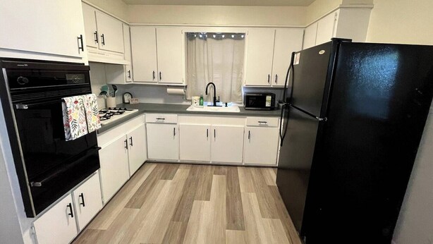 A kitchen with white cabinets, a black refrigerator, a microwave, and a stove. - 🏡 Spacious Stay on Bridge – 4BR / 2BA<br><br>Comfortable 4-bedroom, 2-bath home perfect for families or groups, with bright living areas, a full kitchen, and a convenient Abilene location. 🌟 (Abilene)