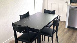 A dining area with a black marble table and four chairs, a white door, and a kitchen area with a microwave. - 🏡 Abilene Restful Retreat – 2BR / 2BA ✨<br>Enjoy a cozy and relaxing stay in Abilene. This comfortable home is perfect for families, friends, or business travelers and is conveniently located near restaurants, shopping, and local attractions. 🌟 (Abilene)
