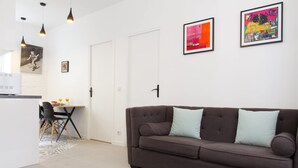 Ein modernes Wohnzimmer mit einer braunen Couch, einem Esstisch mit Stühlen und einer Küchenzeile.