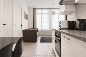 Une cuisine moderne équipée d’un four encastré, d’une machine à café et d’une bouilloire posées sur le plan de travail.