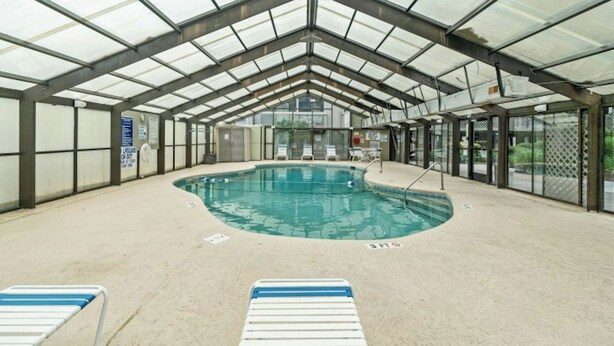 Une piscine intérieure dotée d’un toit en verre, de chaises longues et d’un poste de surveillance pour les sauveteurs.