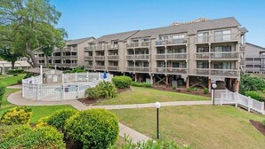 Un hôtel à plusieurs étages doté de balcons, d’une cour intérieure et d’une pelouse bien entretenue.