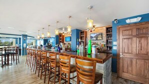 Un espace bar avec des chaises en bois, un comptoir et des lampes suspendues.
