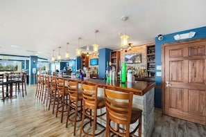 Un espace bar avec des chaises en bois, un comptoir et des lampes suspendues.