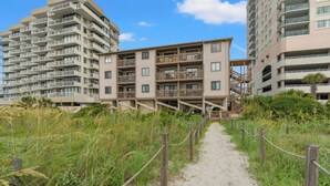 A pathway leading to a multi-story building with balconies and a staircase. - Crescent Villas 302- 2 Bedroom Condo- Pool (North Myrtle Beach)