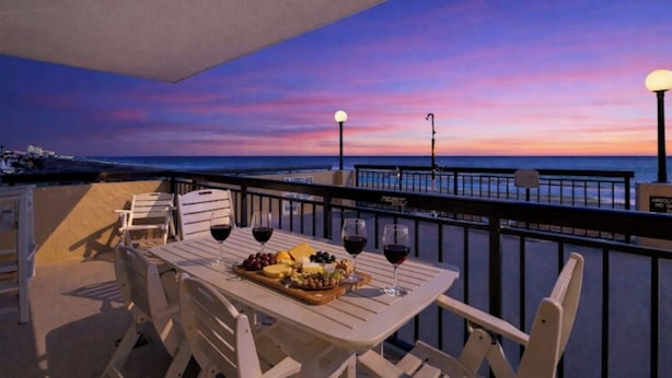Ein Balkon mit Tisch für zwei Personen, Sonnenuntergangblick und Geländer.