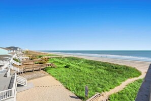 A beach view with a grassy area, wooden walkways, and a clear sky. - Buena Vista 401-Oceanfront 3BR Condo- Cherry Grove (North Myrtle Beach)