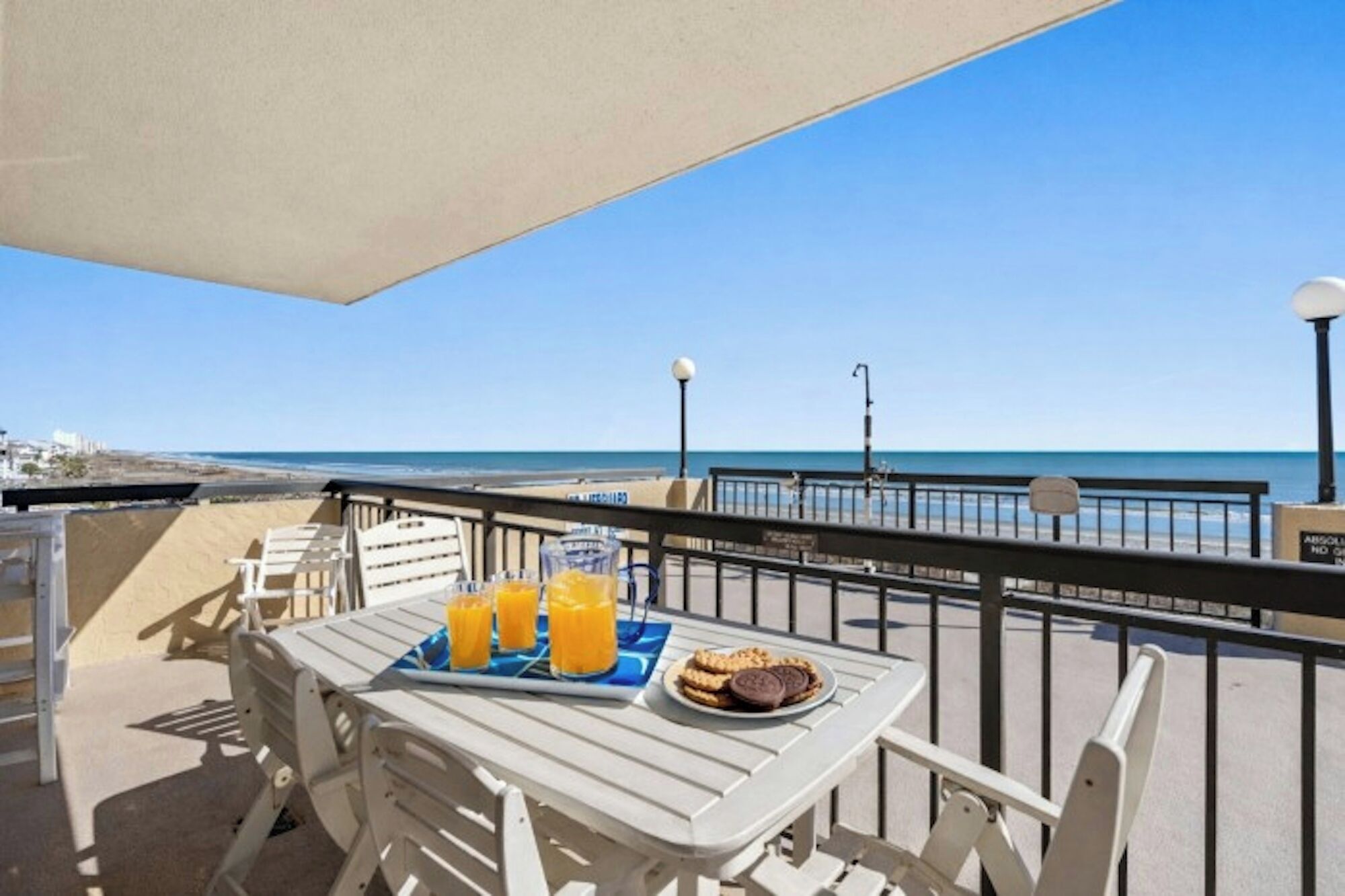 Un balcón con una mesa preparada para el desayuno, con vistas a la playa y al mar.