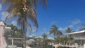A waterfront property with a covered patio, outdoor seating, and a dock. - Ocean Breeze Retreat/ Elegant 3/3 in Marathon/ Coastal Luxury Living (Marathon)