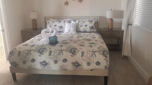 A bedroom with a bed, two nightstands, a ceiling fan, and a window with blinds. - Ocean Breeze Retreat/ Elegant 3/3 in Marathon/ Coastal Luxury Living (Marathon)