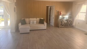 A living room with a sofa, a cabinet, and a door leading to another room. - Ocean Breeze Retreat/ Elegant 3/3 in Marathon/ Coastal Luxury Living (Marathon)