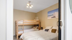 Een slaapkamer met stapelbedden, een plafondlamp, een schilderij en een radiator.