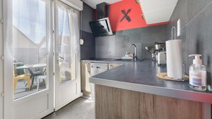 Een moderne keuken met een inbouwmagnetron, een spoelbak en een aanrecht met een zeepdispenser.