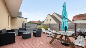 Un patio con mobili da esterno, un tavolo e un ombrellone.