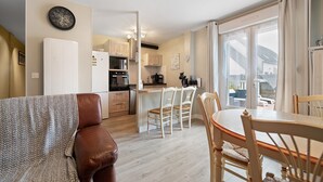 Una cucina moderna con mobili bianchi, un'area pranzo con tavolo e sedie in legno, e un'ampia finestra con tende.