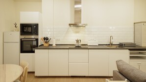 Una cocina moderna con horno empotrado, microondas, campana extractora de acero inoxidable y una isla grande con lavaplatos.