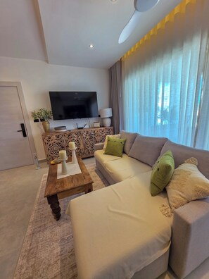 Ein modernes Wohnzimmer mit Flachbildfernseher, Couchtisch aus Holz, beiger Couch und einer dekorativen Konsole.